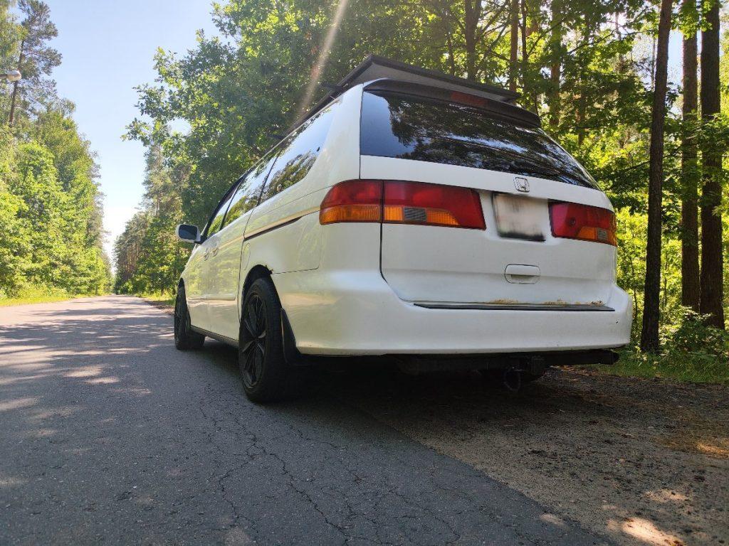 Honda Odyssey parked on forest road with camping gear