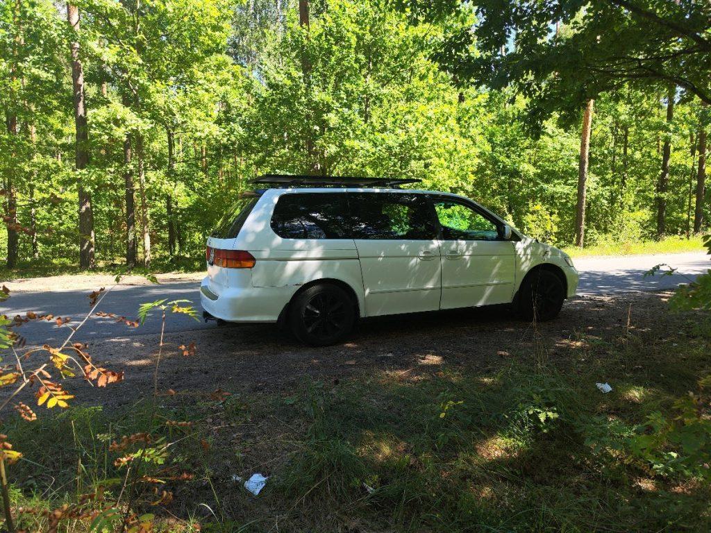 Honda Odyssey camping in forest with campfire site