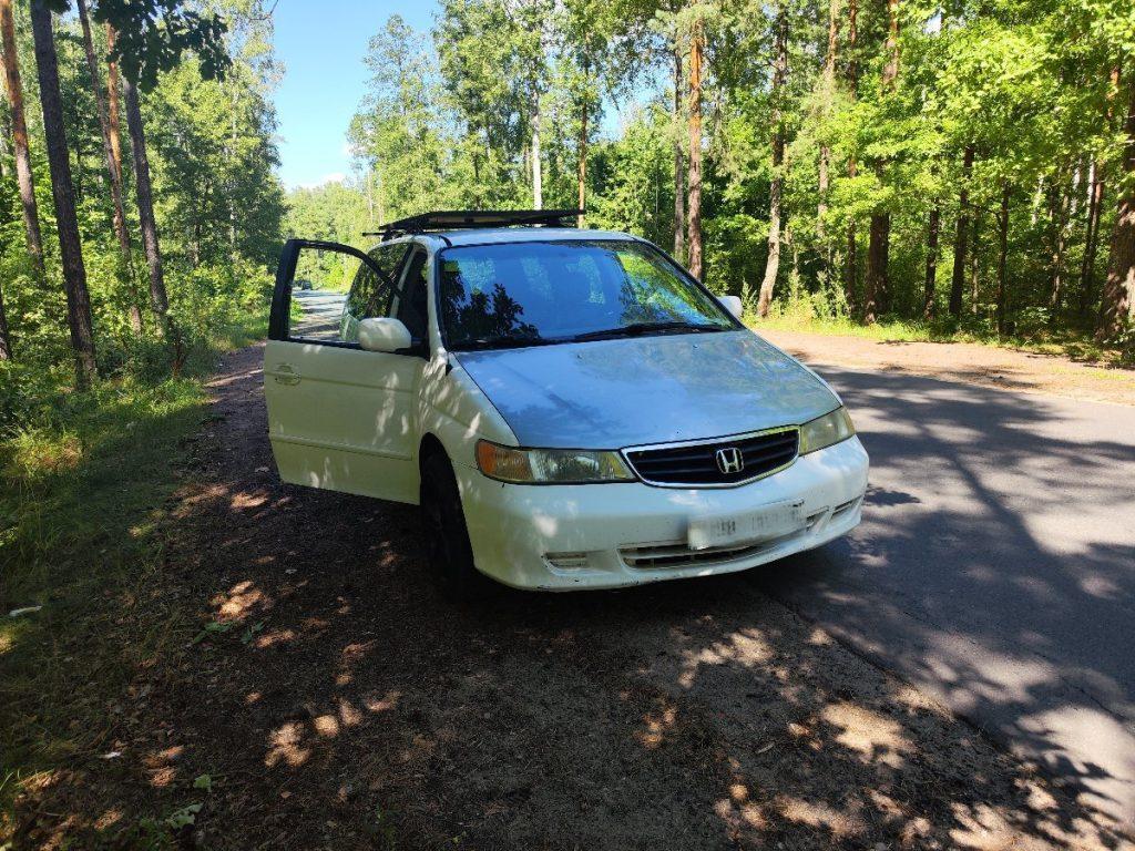 Honda Odyssey driver side view on forest road with roof rack