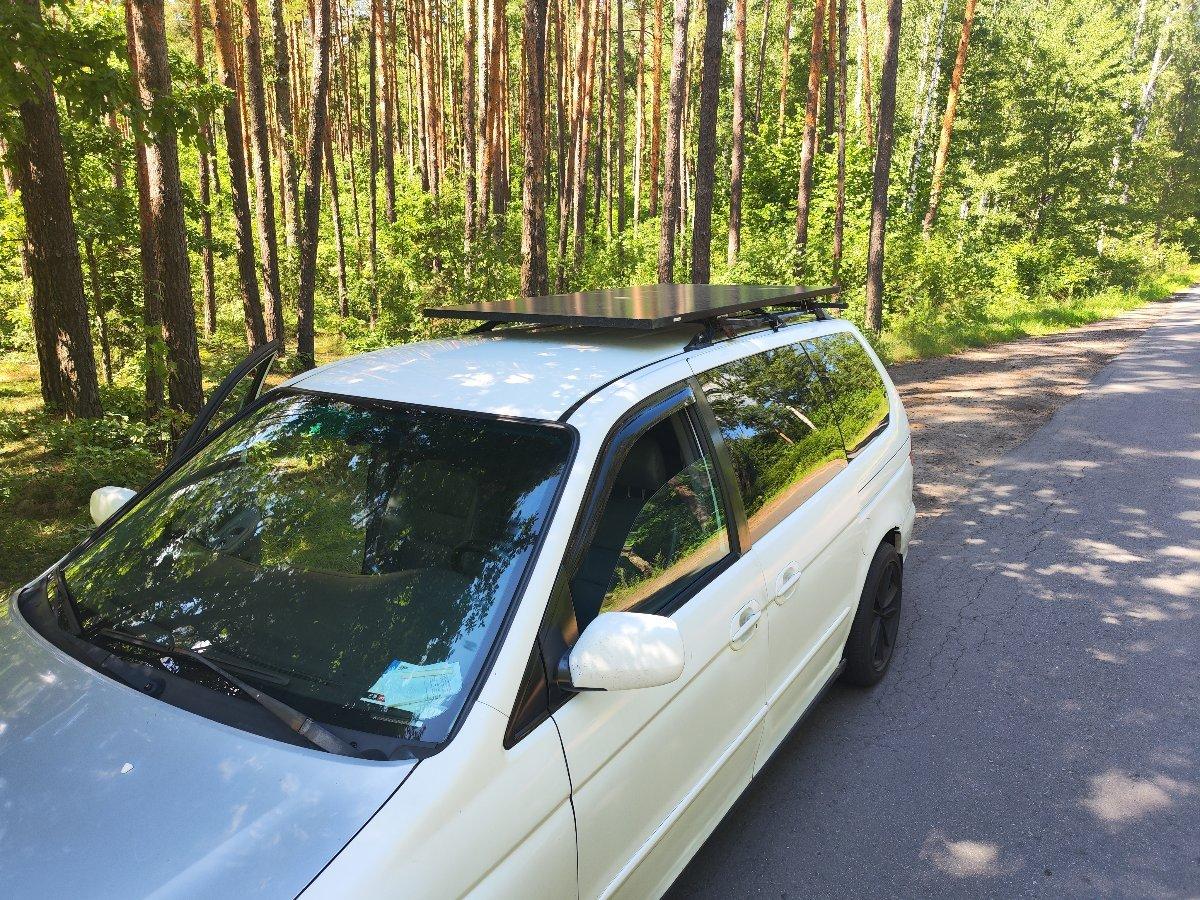 Honda Odyssey minivan parked on forest road with camping setup