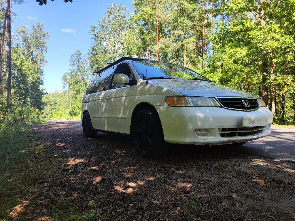 Honda Odyssey minivan camping setup with open doors in forest
