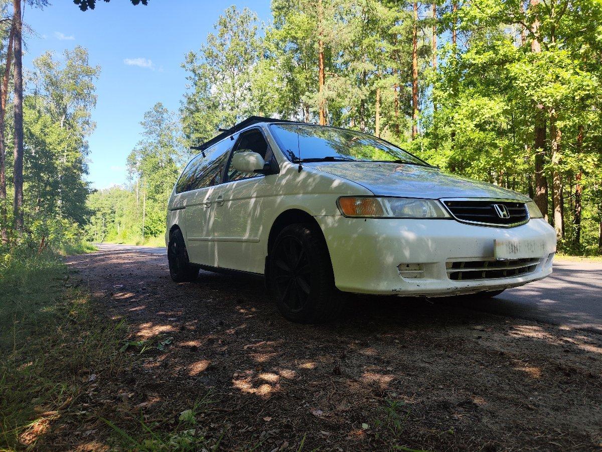 Minivan camping setup with open doors and camping gear in forest