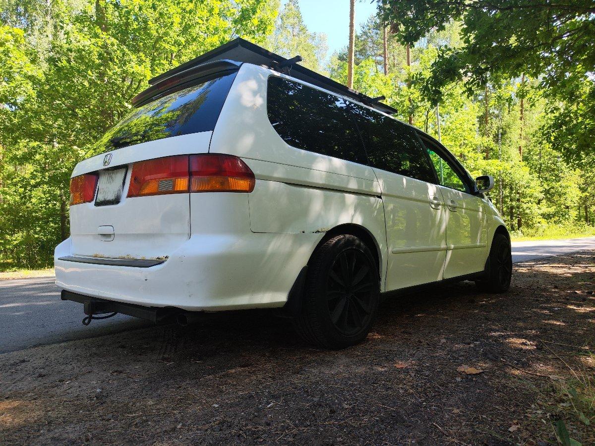 Honda Odyssey with roof rack parked on forest road camping setup