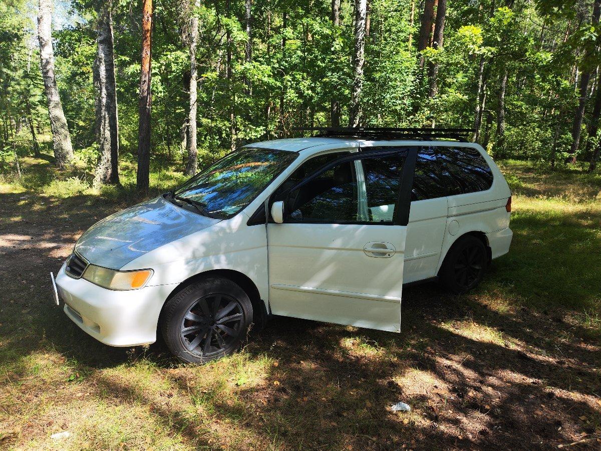Minivan interior with camping gear and sleeping setup for cold weather