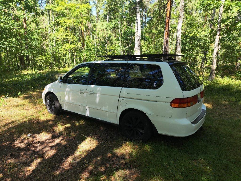 Honda Odyssey rear view with black wheels and roof rack in forest